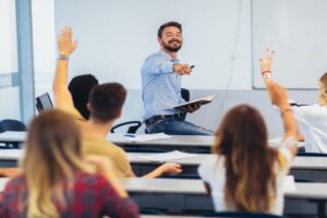 Group of students raising hands in class on lecture
